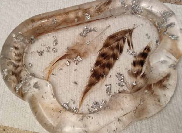 epoxy tray with feathers inside and silver flakes.